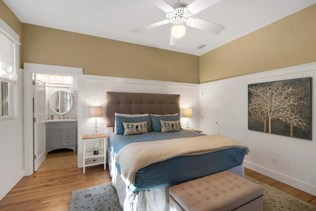 bedroom with ceiling fan, connected bathroom, and wood-type flooring