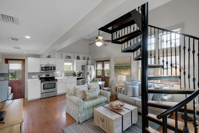 living room with a high ceiling, dark wood-type flooring, ceiling fan, and sink