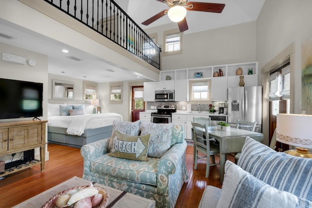 living room featuring sink, a high ceiling, ceiling fan, and light hardwood / wood-style flooring