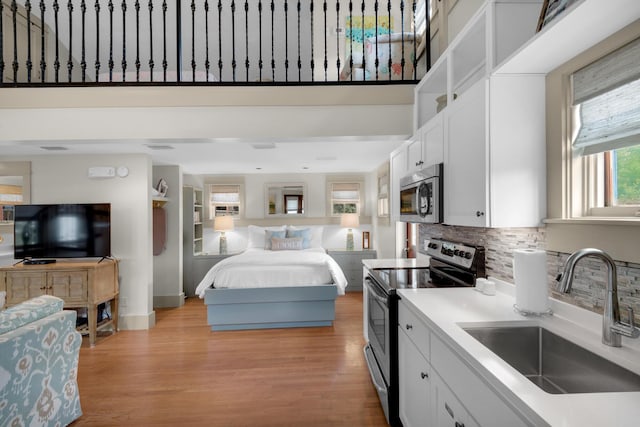 kitchen with stainless steel appliances, white cabinets, sink, and backsplash