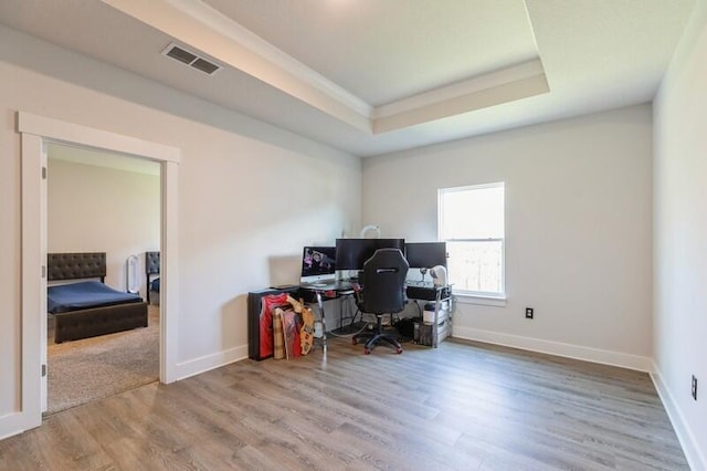 office space with a tray ceiling and hardwood / wood-style flooring