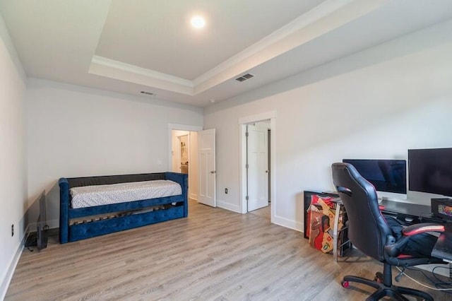 bedroom featuring hardwood / wood-style flooring, crown molding, and a raised ceiling