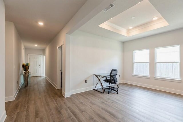 home office with hardwood / wood-style floors and a raised ceiling