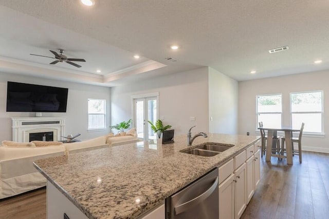 kitchen featuring sink, light stone counters, stainless steel dishwasher, an island with sink, and white cabinets