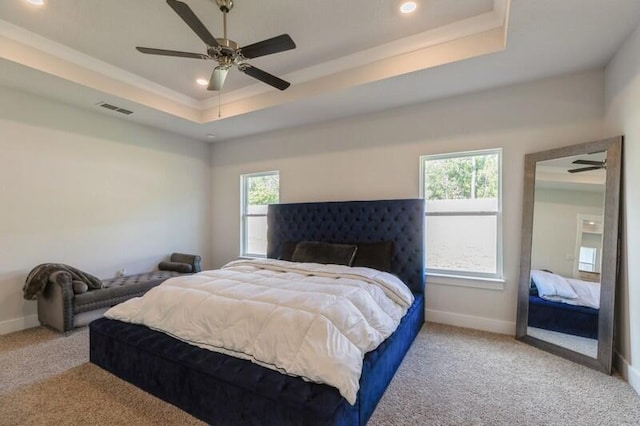 carpeted bedroom featuring ceiling fan and a tray ceiling