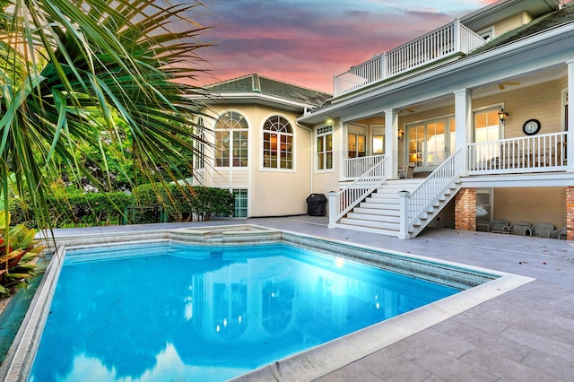 pool at dusk with a patio area