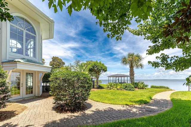 view of yard featuring a gazebo, a patio area, french doors, and a water view