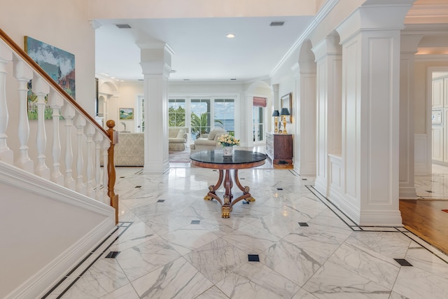 foyer featuring crown molding and decorative columns