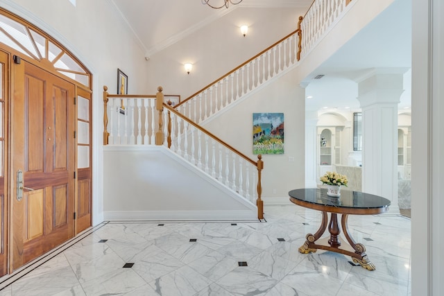 entryway with a towering ceiling, ornamental molding, and decorative columns