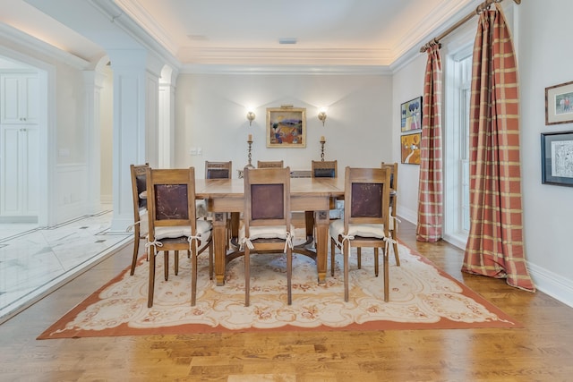 dining room featuring ornate columns, crown molding, and hardwood / wood-style floors