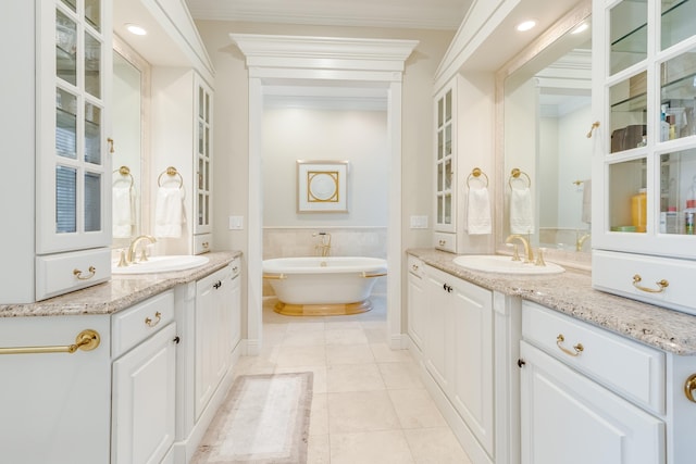 bathroom with tile patterned flooring, ornamental molding, a bathing tub, and vanity