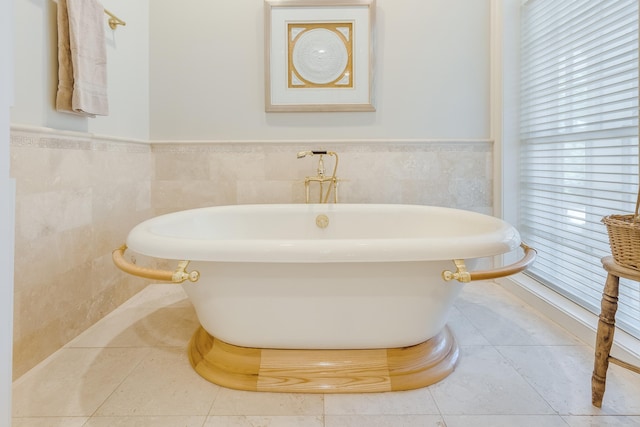 bathroom with a washtub, tile patterned floors, and tile walls