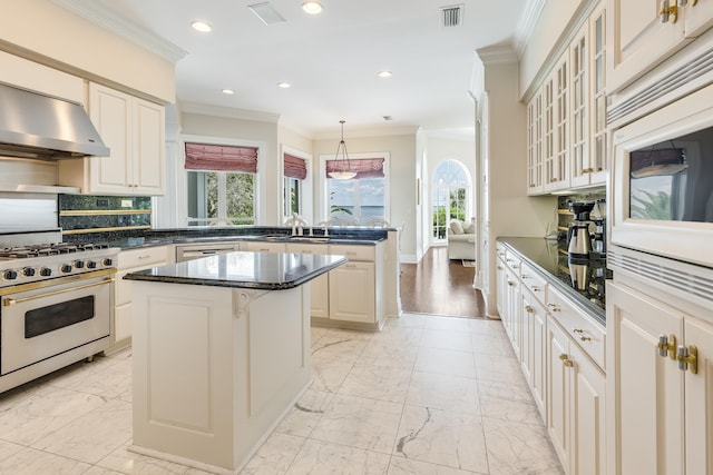 kitchen with a kitchen island, tasteful backsplash, hanging light fixtures, exhaust hood, and stainless steel appliances