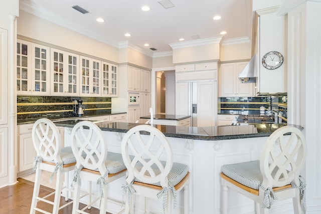 kitchen featuring paneled fridge, a breakfast bar, and kitchen peninsula