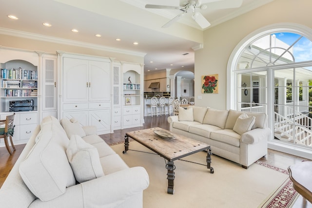 living room featuring ceiling fan, ornamental molding, and light hardwood / wood-style floors