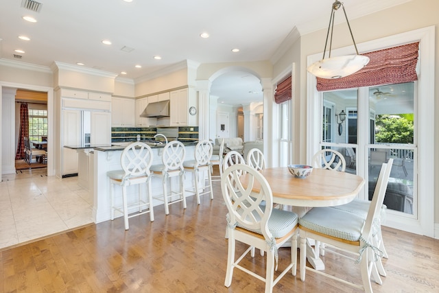 dining space with crown molding, light hardwood / wood-style floors, and ornate columns