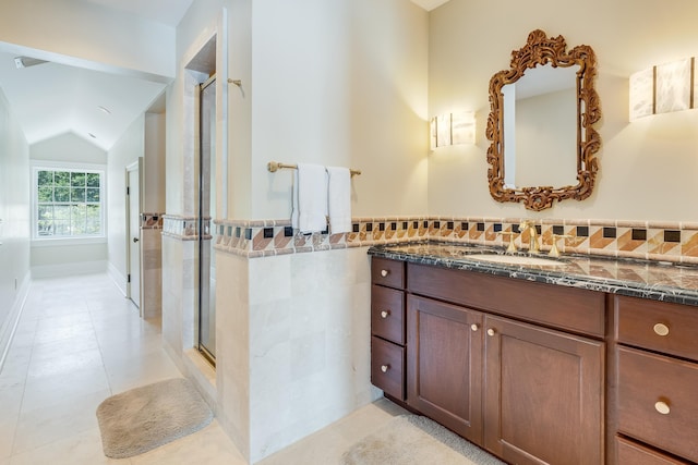 bathroom featuring vaulted ceiling, tile walls, tile patterned flooring, vanity, and walk in shower