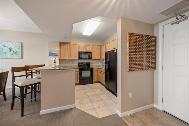 kitchen featuring black appliances, light brown cabinetry, light stone counters, kitchen peninsula, and a breakfast bar area