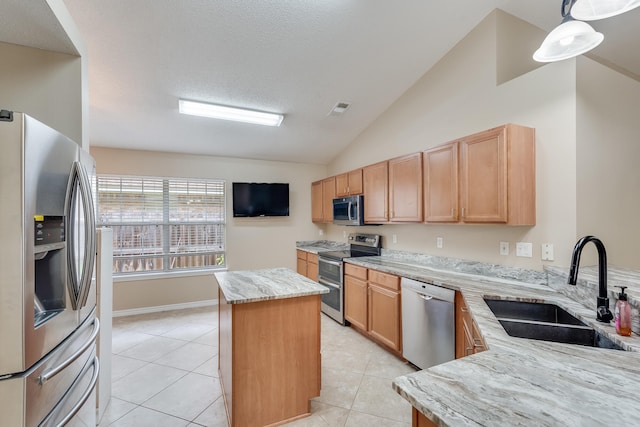 kitchen with lofted ceiling, a kitchen island, appliances with stainless steel finishes, pendant lighting, and sink