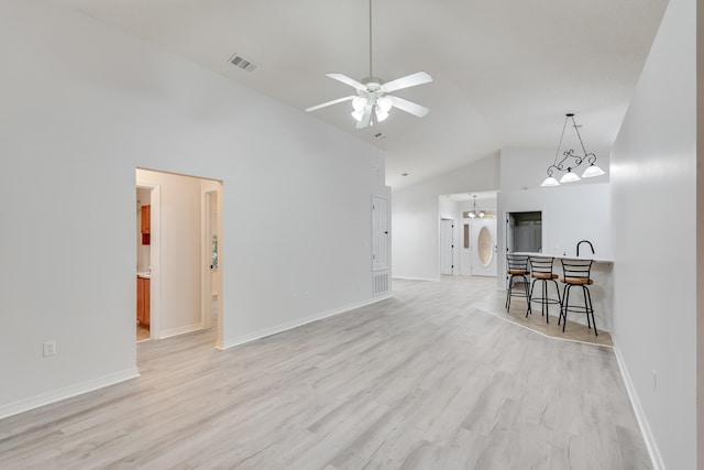 living room with high vaulted ceiling, light wood-type flooring, and ceiling fan with notable chandelier