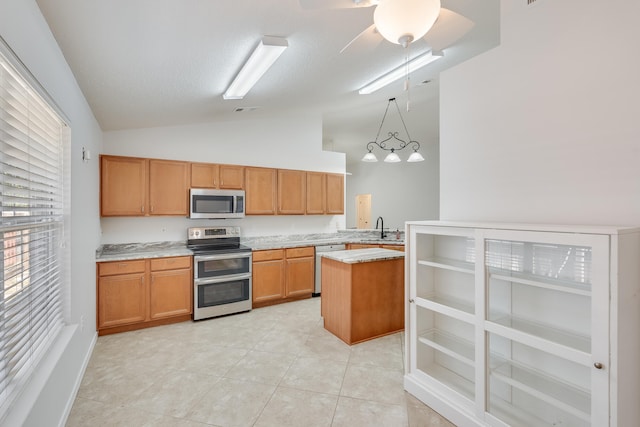 kitchen with appliances with stainless steel finishes, sink, light tile patterned flooring, lofted ceiling, and decorative light fixtures