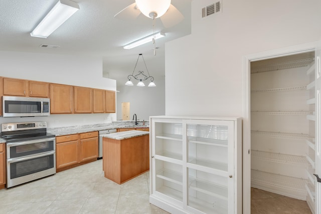 kitchen featuring a center island, hanging light fixtures, stainless steel appliances, lofted ceiling, and light tile patterned floors