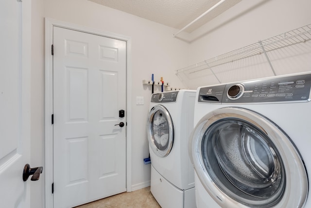 laundry room featuring a textured ceiling, light tile patterned flooring, and washer and clothes dryer