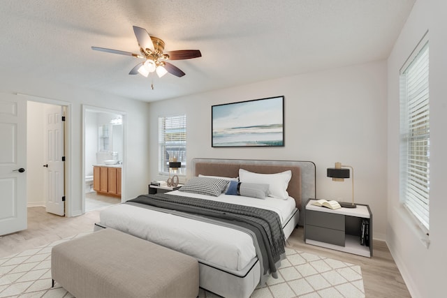 bedroom featuring light hardwood / wood-style floors, a textured ceiling, connected bathroom, and ceiling fan