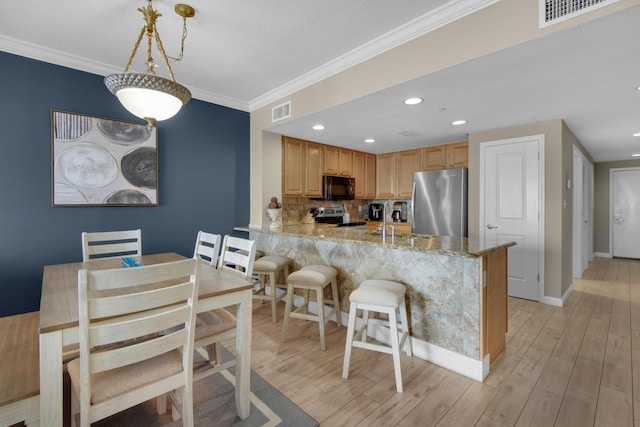 kitchen with hanging light fixtures, light stone counters, kitchen peninsula, crown molding, and appliances with stainless steel finishes