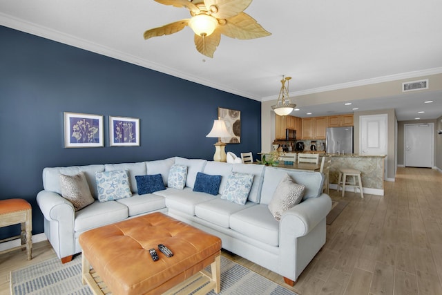 living room with ceiling fan, ornamental molding, and light hardwood / wood-style flooring