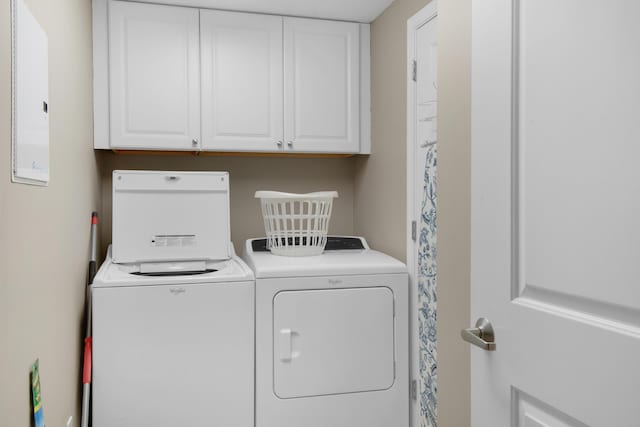 clothes washing area with washer and dryer and cabinets