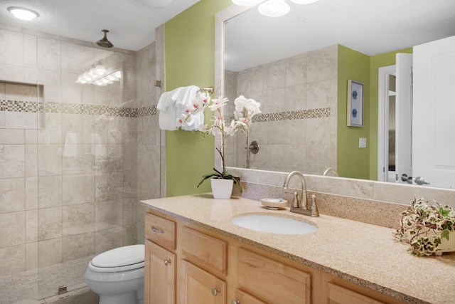 bathroom with tiled shower, vanity, and toilet