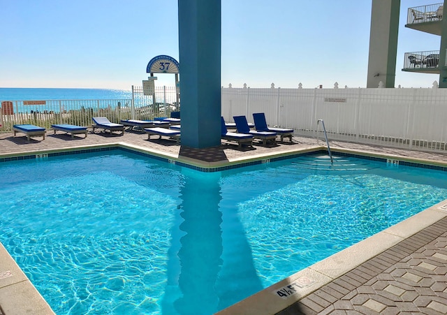 view of swimming pool featuring a water view and a patio