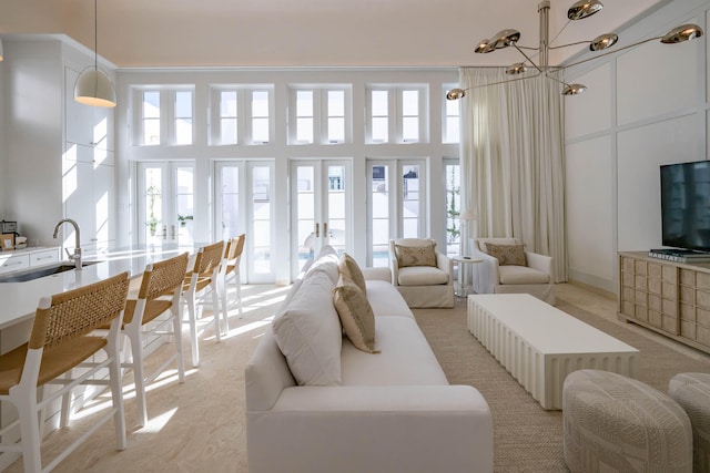 living room with a towering ceiling, sink, and a chandelier