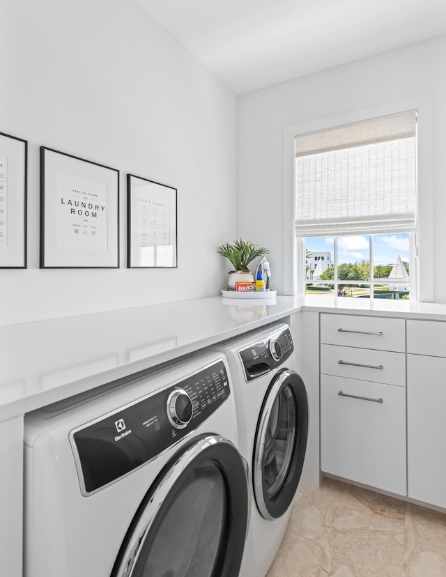 laundry room with light tile patterned floors, cabinets, and washer and clothes dryer