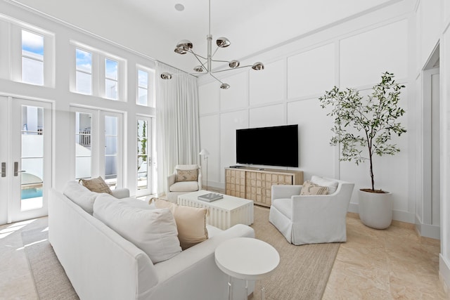 living room featuring french doors, light tile patterned floors, a chandelier, and a towering ceiling