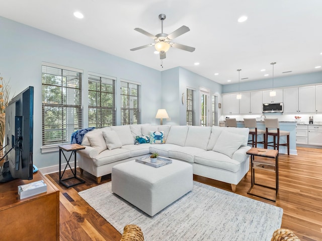 living room with light hardwood / wood-style floors and ceiling fan