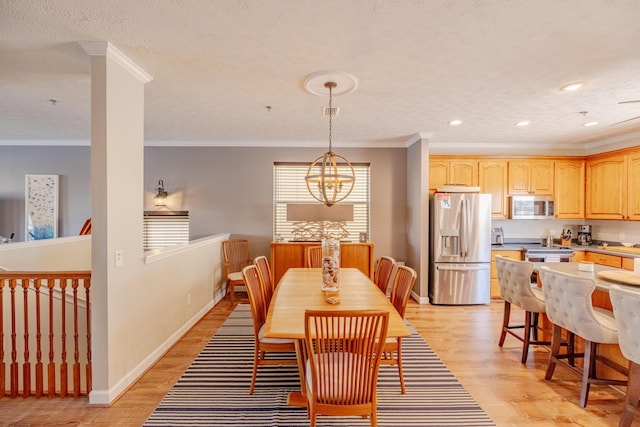 dining space featuring a notable chandelier, ornamental molding, a textured ceiling, light wood finished floors, and baseboards