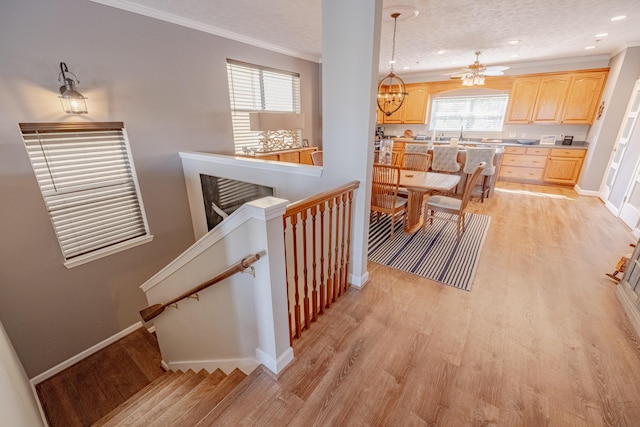 stairs with baseboards, a textured ceiling, wood finished floors, and crown molding