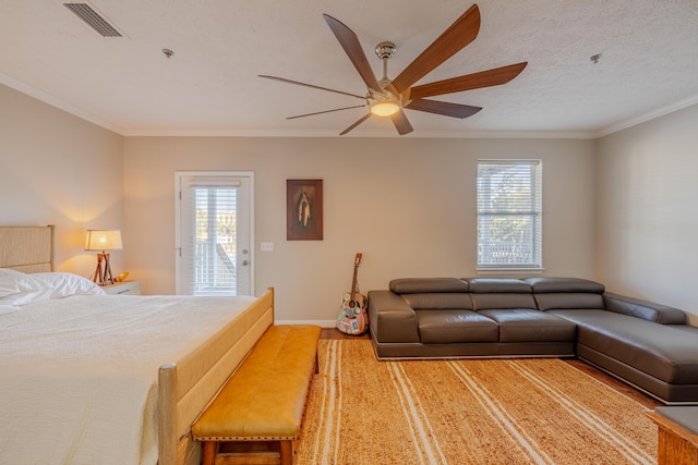 bedroom with a textured ceiling, crown molding, baseboards, and wood finished floors