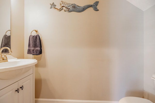 bathroom with baseboards, toilet, and vanity