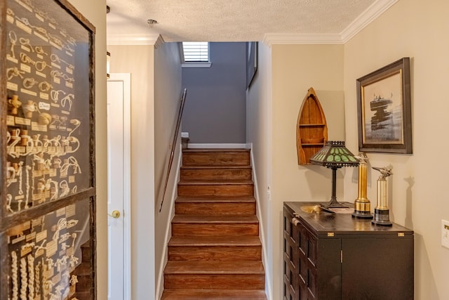 stairs with a textured ceiling, crown molding, and wood finished floors