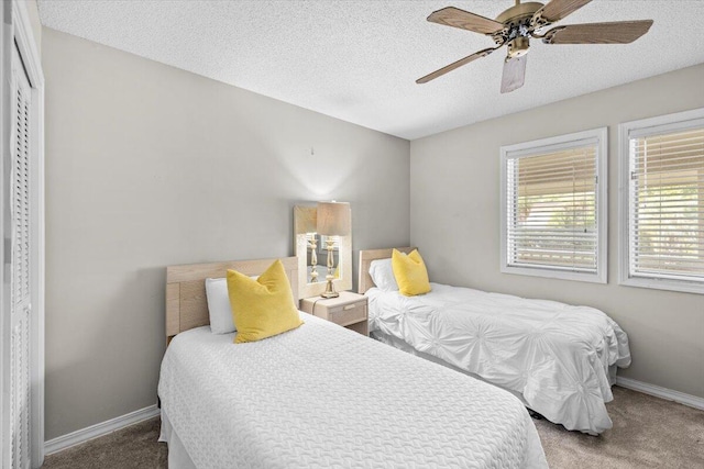 carpeted bedroom with a textured ceiling, ceiling fan, and baseboards