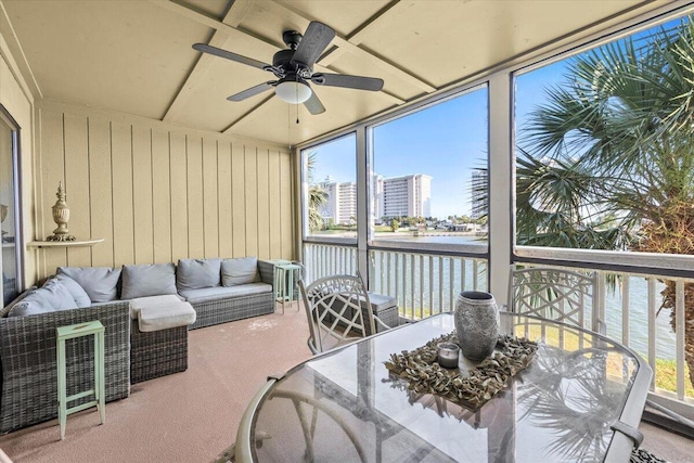 sunroom featuring a water view, a ceiling fan, and a healthy amount of sunlight