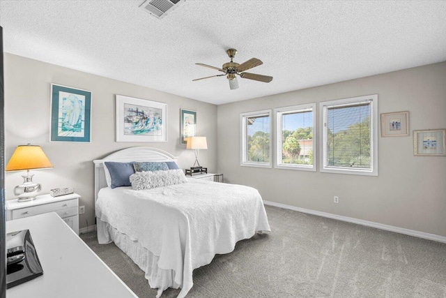 carpeted bedroom with a ceiling fan, visible vents, a textured ceiling, and baseboards