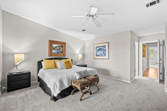 bedroom featuring a textured ceiling, light carpet, visible vents, baseboards, and a ceiling fan