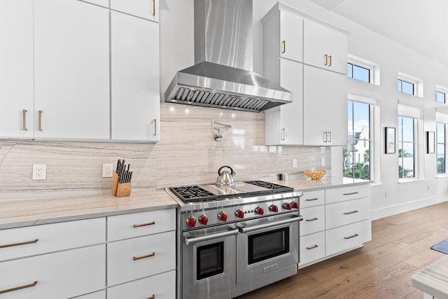 kitchen with exhaust hood, white cabinetry, and double oven range