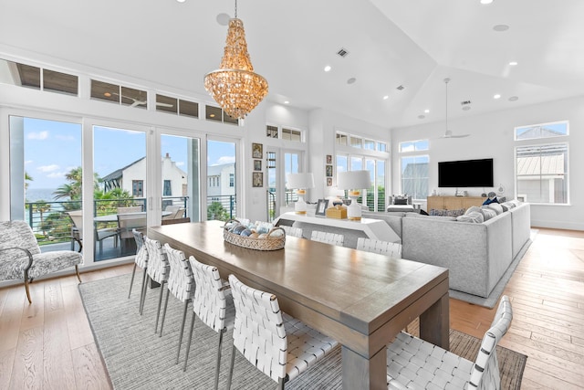 dining area with high vaulted ceiling, light hardwood / wood-style flooring, and a chandelier