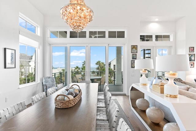 dining room featuring a notable chandelier, a towering ceiling, and hardwood / wood-style flooring