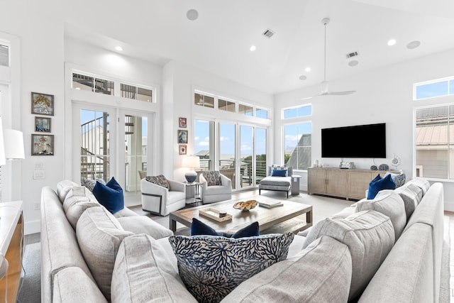 living room with ceiling fan, a wealth of natural light, and a high ceiling